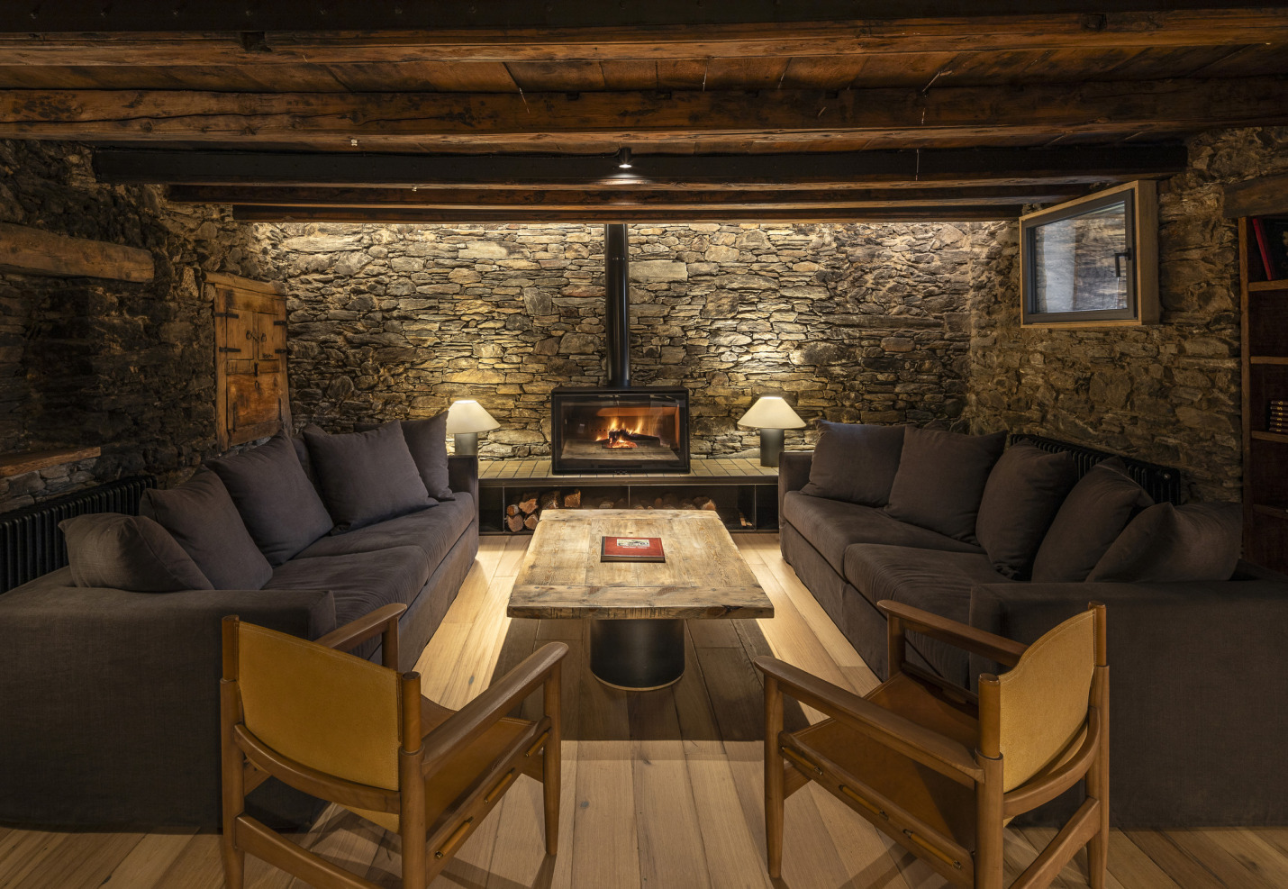 sala estar amb llar de foc i paret de pedra rehabitlitada