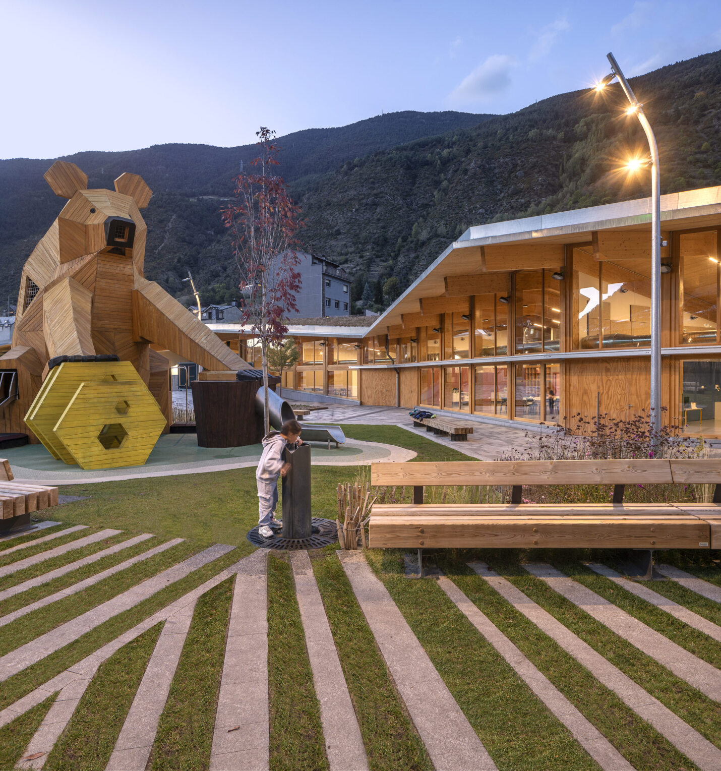 ossa amb font en primer pla i edifici amb la llum encesa